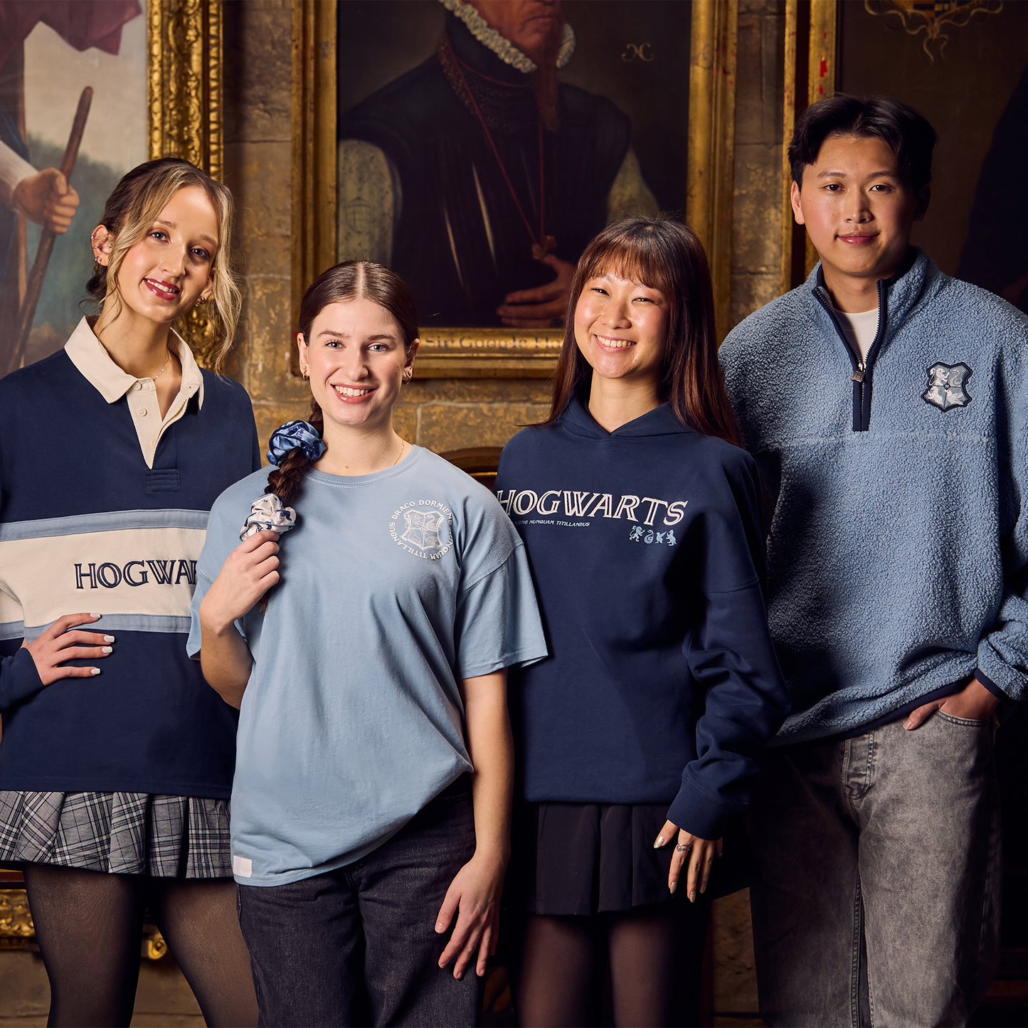 Four people wearing Hogwarts-themed clothing in a room with classical painting.