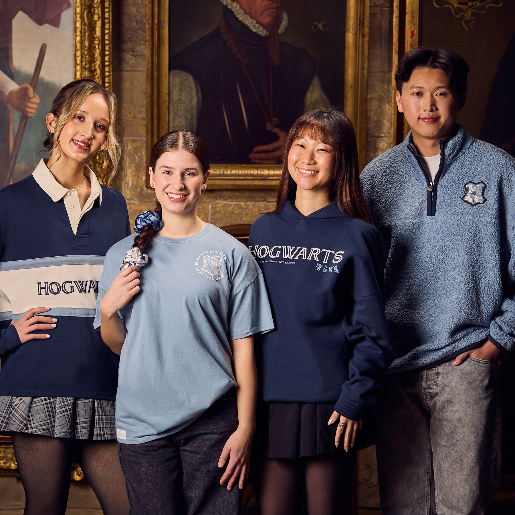 Four people wearing Hogwarts-themed clothing in a room with classical painting.