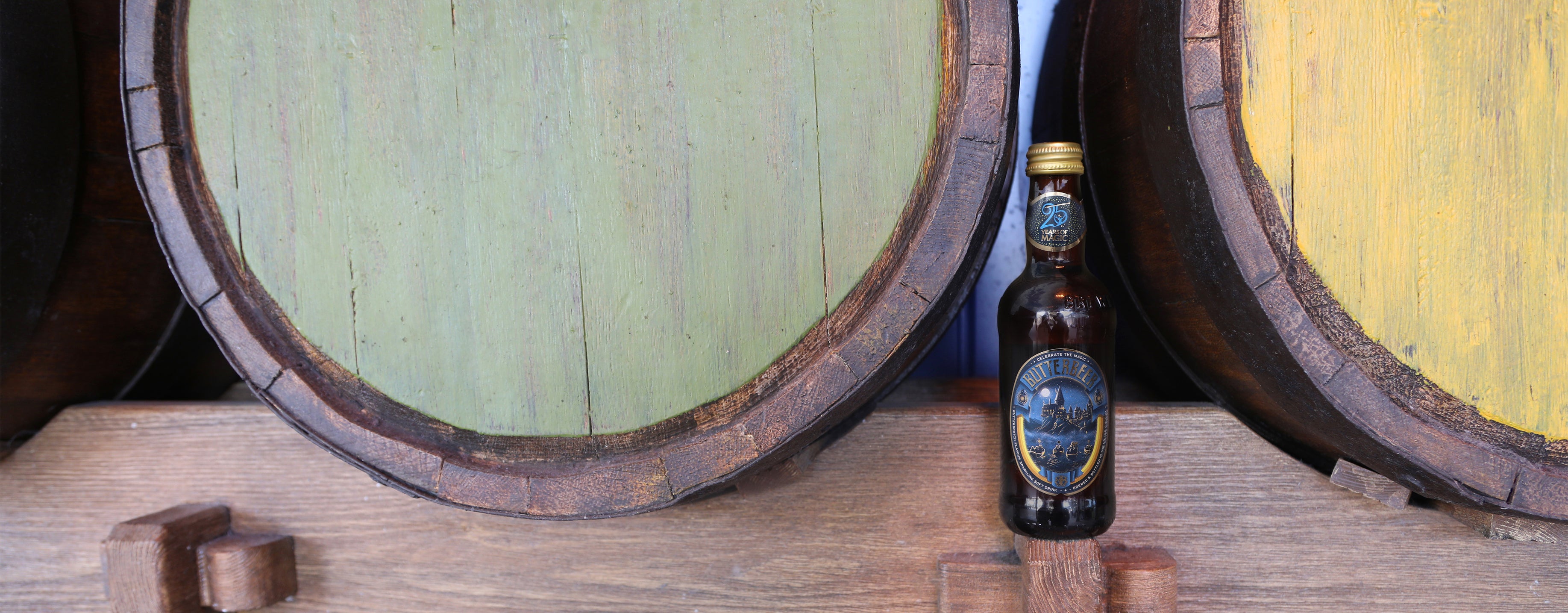 Bottle of Butterbeer in front of wooden barrels