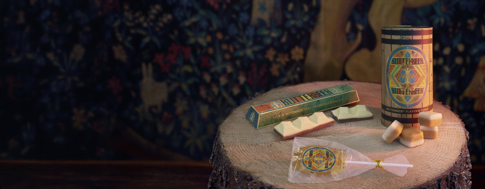 Vintage-style setting with a tin of Butterbeer fudge, and other Butterbeer confectionery on a wooden table.
