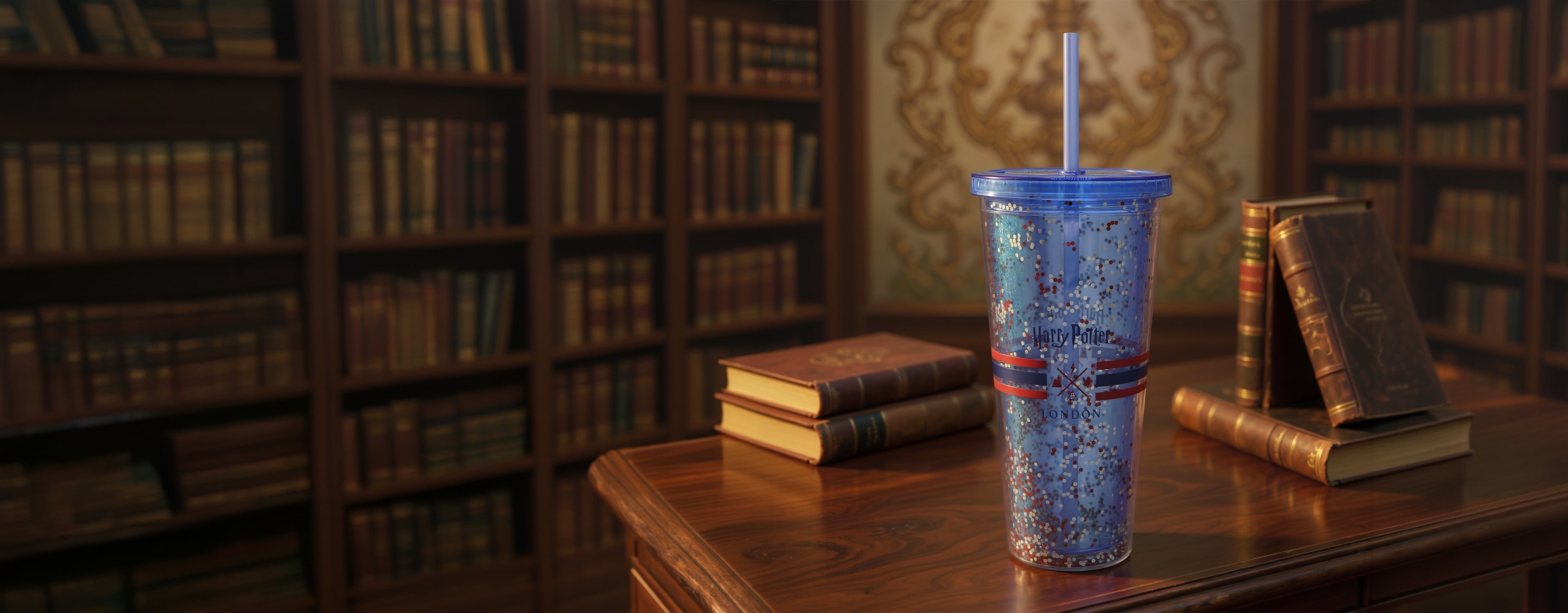 Blue glittery tumbler with a straw on a wooden table in a library setting