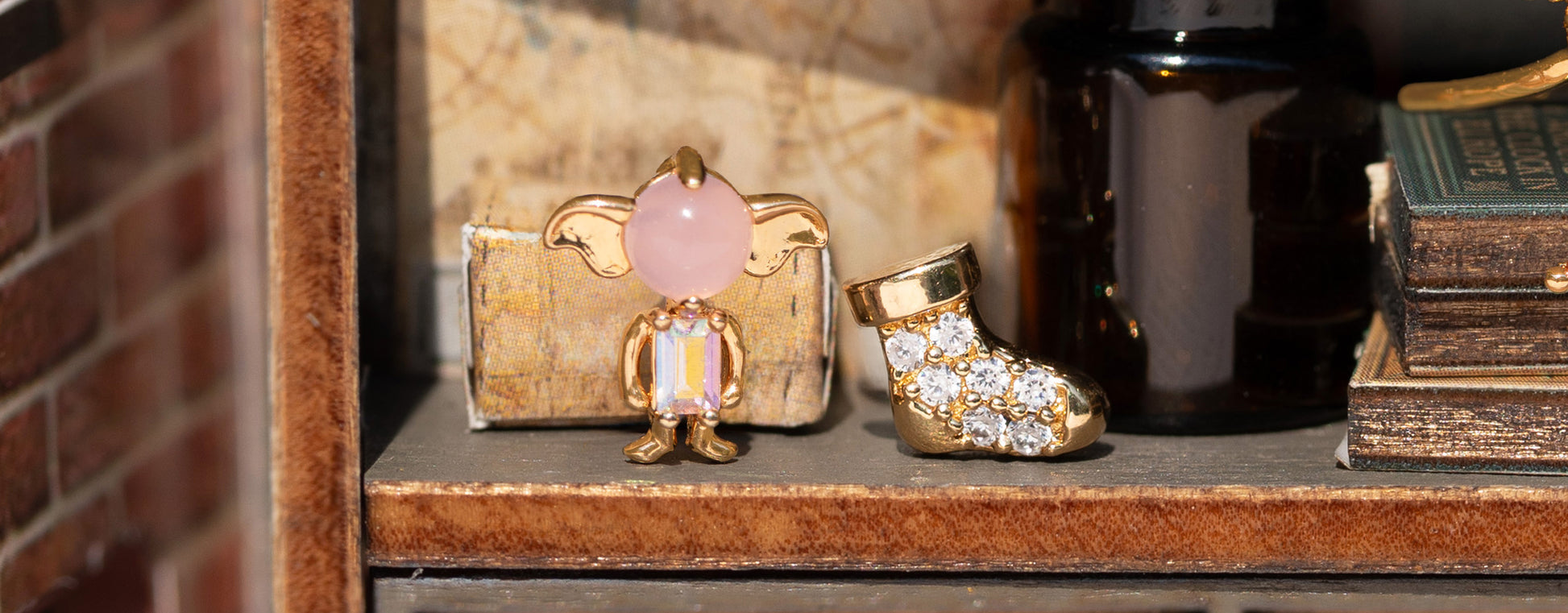 Decorative earrings including a gold sock and pink gemstone Dobby on a shelf.