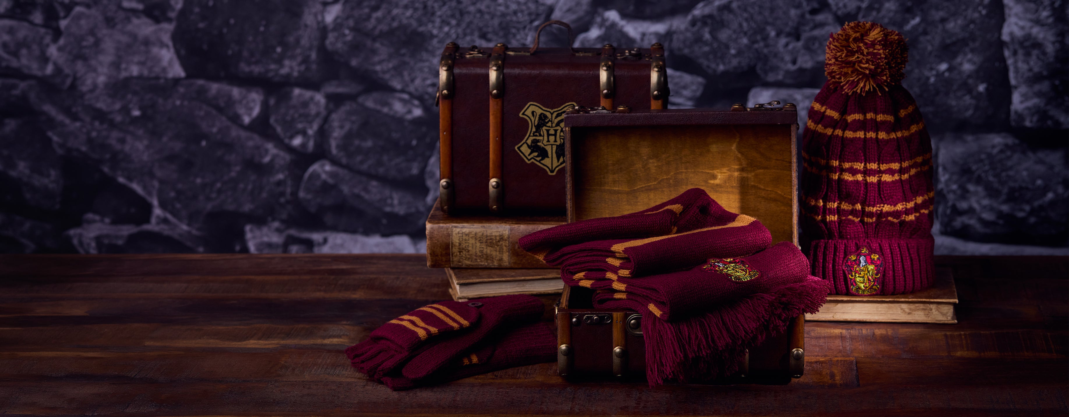 Wooden Hogwarts mini trunk with books and a hat on a dark stone background