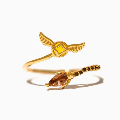 Gold ring with Golden Snitch design and gemstone on a white background