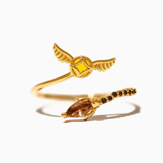 Gold ring with Golden Snitch design and gemstone on a white background