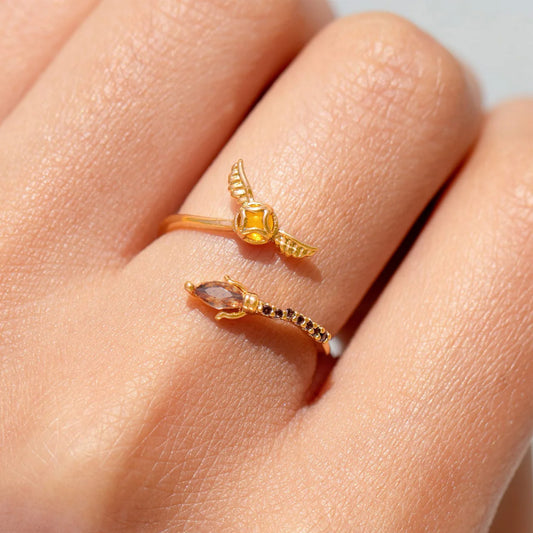 Golden Snitch ring with gemstones on a person's finger