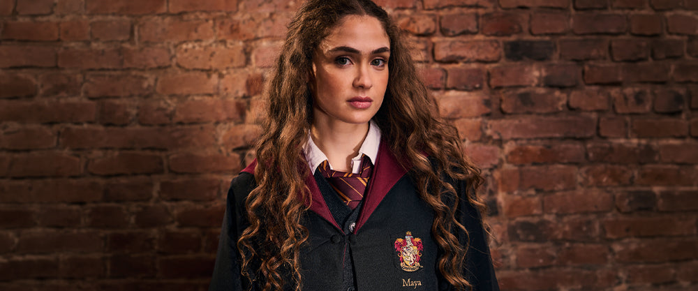 Person wearing a Gryffindor school uniform with a maroon tie against a brick wall