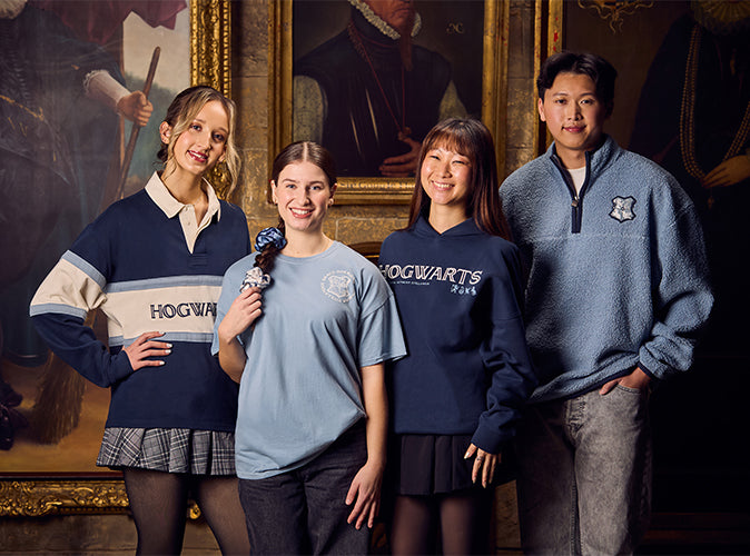 Four people wearing Hogwarts-themed clothing in a room with paintings on the wall.