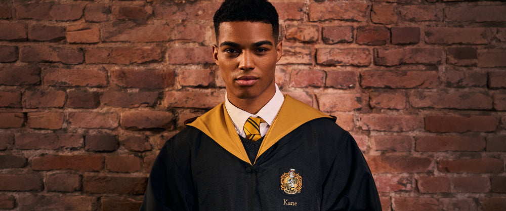 Person wearing a Hufflepuff robe with a school emblem against a brick wall.