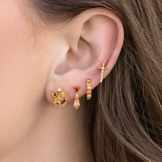 Close-up of an ear wearing gold earrings with gemstones.