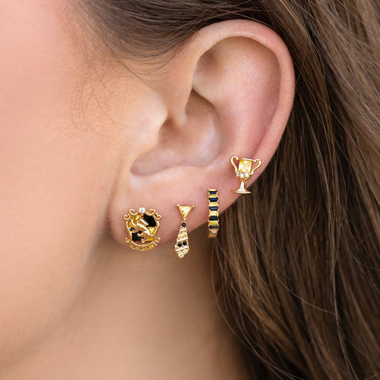 Close-up of an ear wearing gold Hufflepuff earrings with intricate designs.
