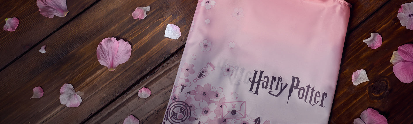 Pink 'Harry Potter' bag with sakura  flower petals on a wooden surface