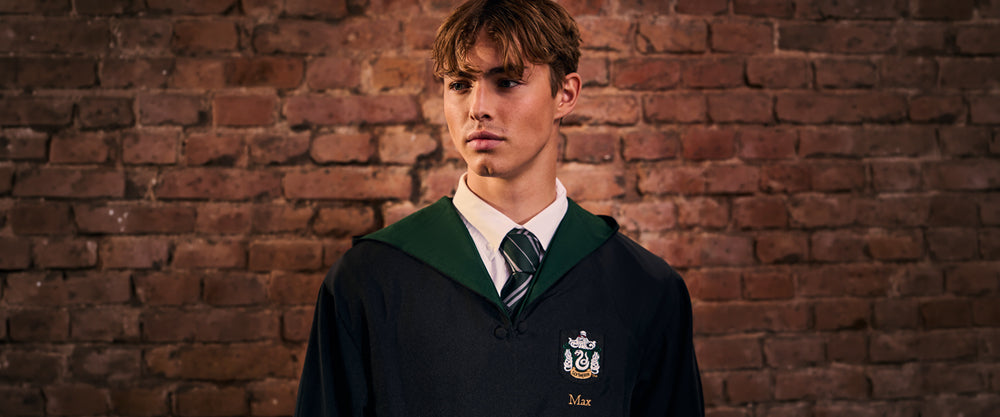 Person wearing a Slytherin uniform with a school emblem against a brick wall.