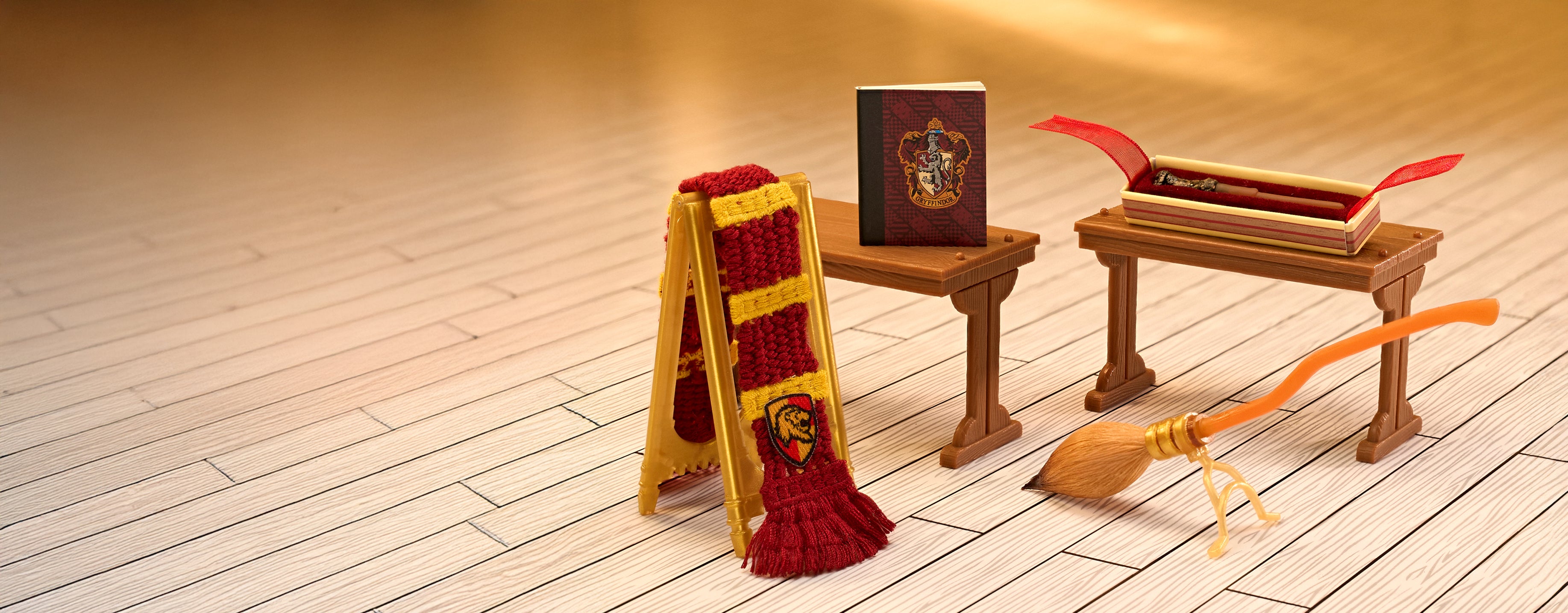 Hogwarts-themed items including a broom, scarf, and books on a wooden floor.